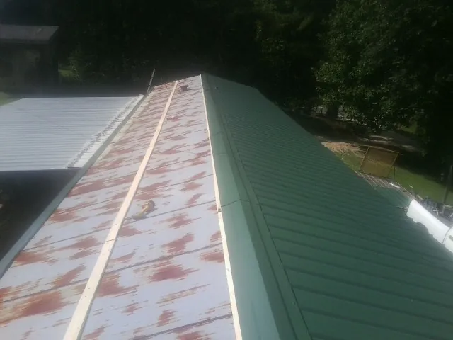 Old rusted panels beside newly installed green metal roofing — Wind Damage Roof Repair by Roofing Brothers in Clarkfield