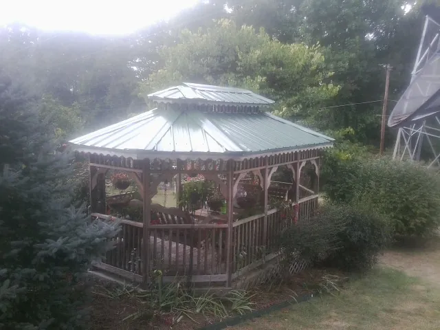 Green metal roof on a backyard gazebo surrounded by garden beds in Clarkfield