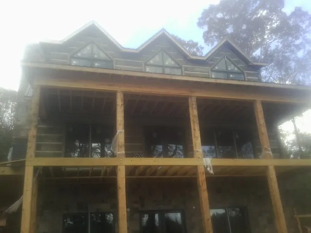 Dormers and porch framing on a large log home under construction — Roof Coating work by our crew in Clarkfield