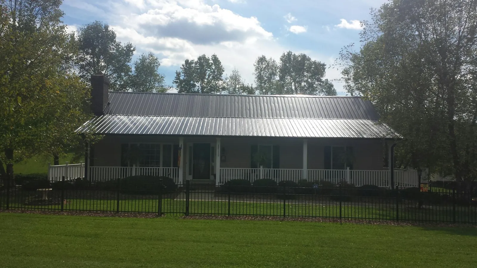 Gray metal roof on a brick ranch with a full width front porch — Gutter Guard Installation work by our crew in Clarkfield