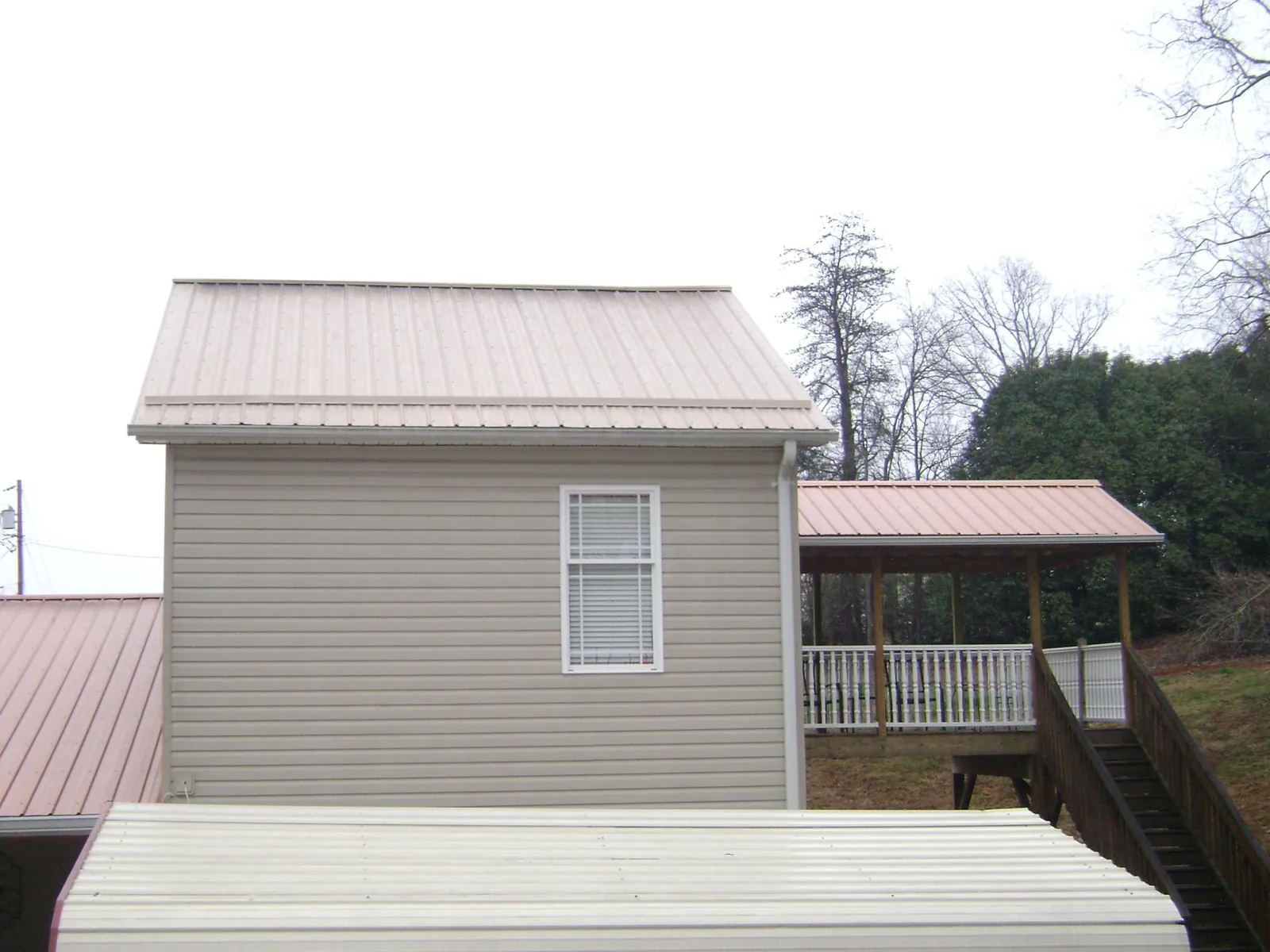 Tan metal roofs on a two story addition and attached porch, from a Roof Replacement job in Clarkfield