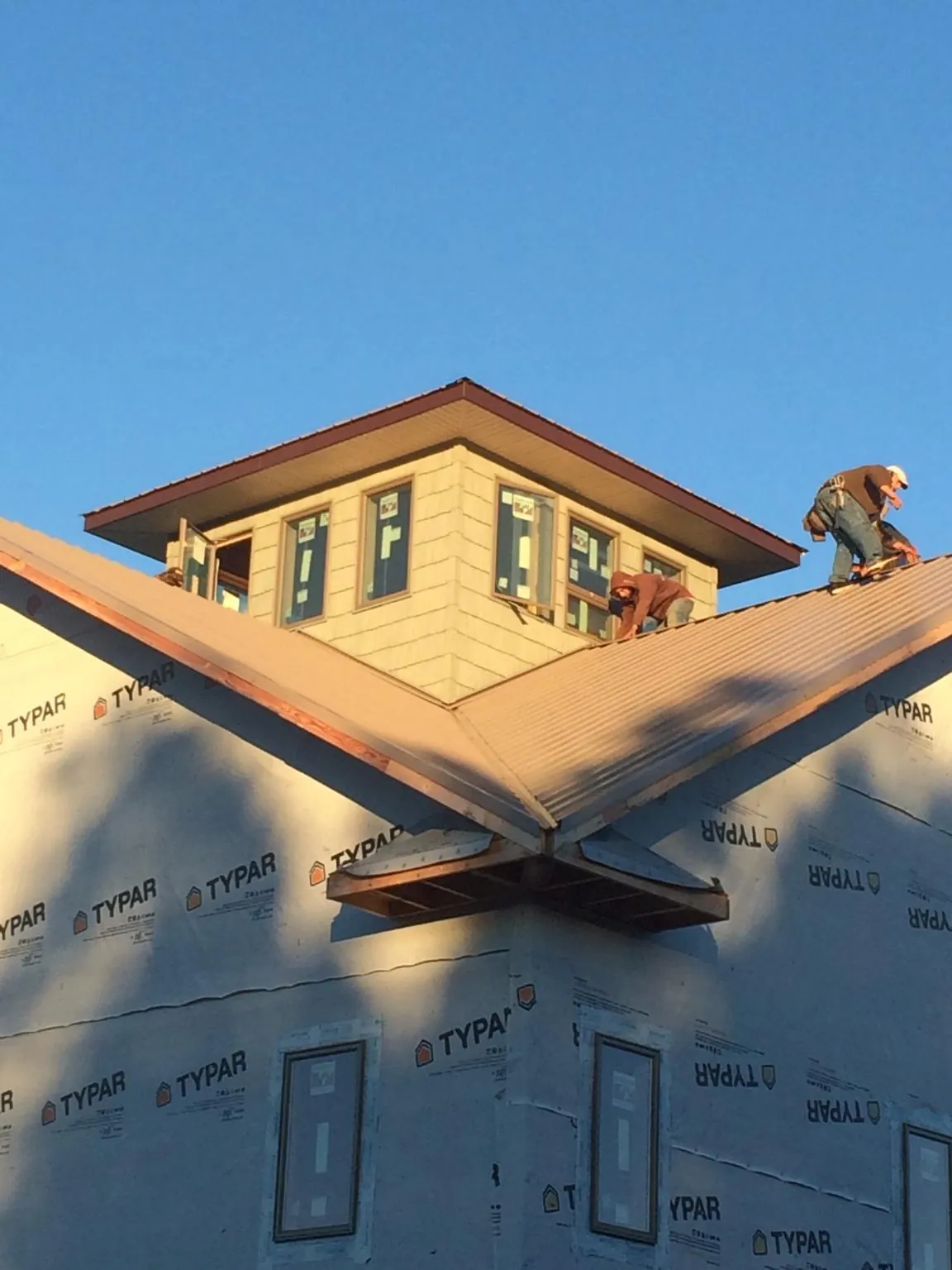 Roofers working around a rooftop cupola on a new metal roof at sunset — Roof Waterproofing in Clarkfield by Roofing Brothers